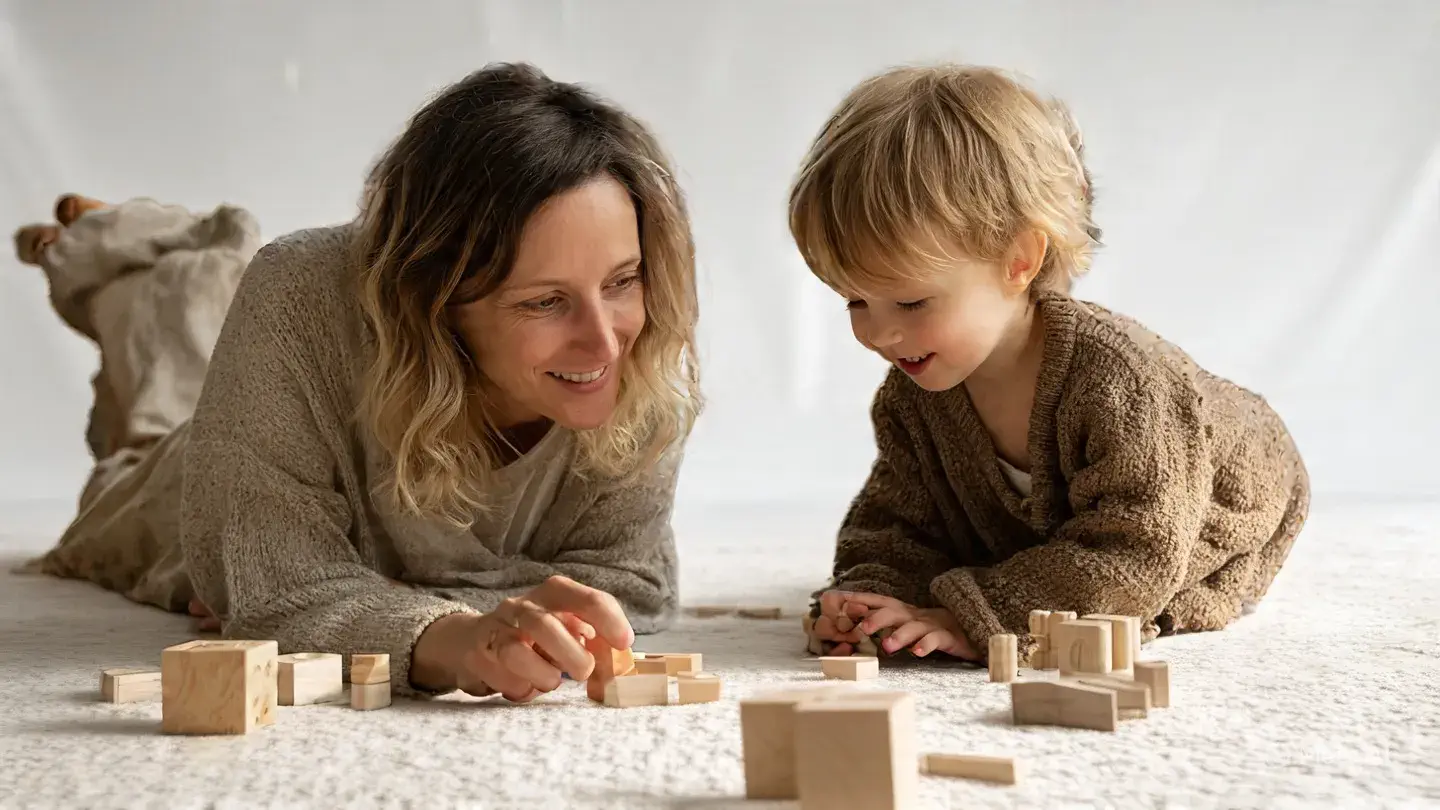 Parent accompagnant son enfant dans un jeu éducatif Montessori en bois.
