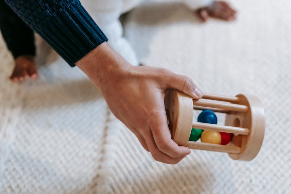 Bébé tenant un hochet en bois coloré pour développer la préhension