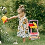Petite fille arrosant son jardin avec un jouet