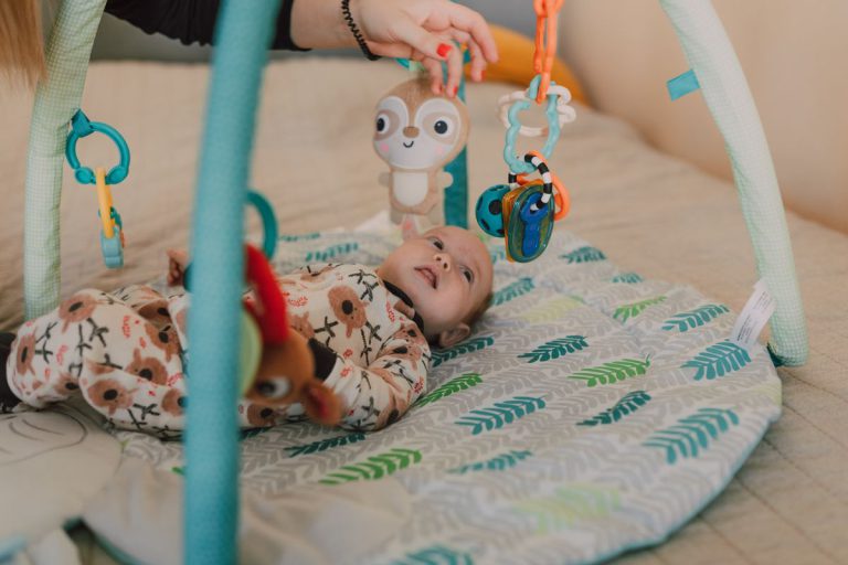 Bébé de 6 mois jouant avec un tapis déveil coloré et des jouets sensoriels