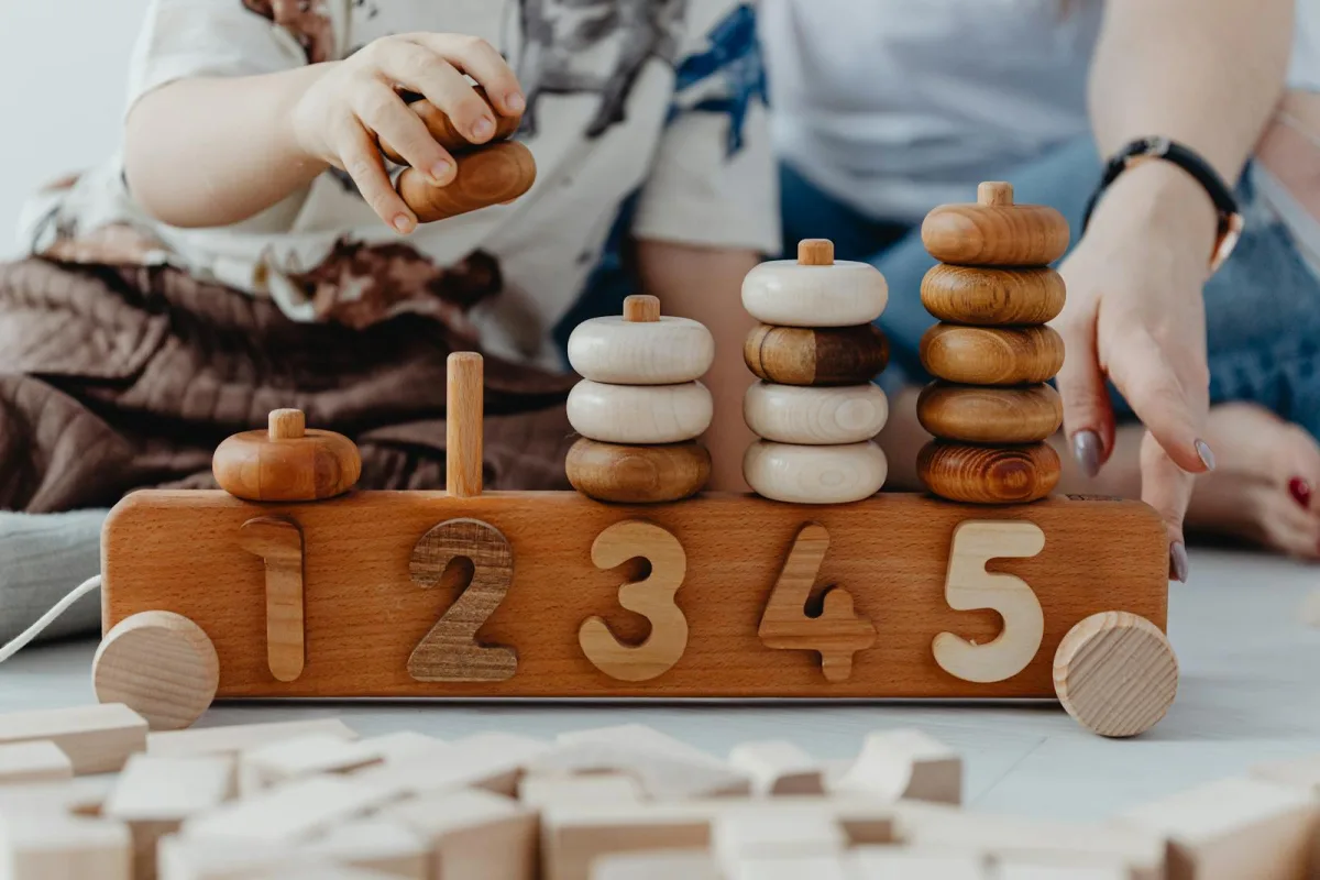 Jeux éducatifs enfant 2 ans - enfant et parent jouant avec des jouets en bois Montessori