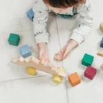 Bébé de 12 mois jouant avec des jouets en bois colorés sur un tapis