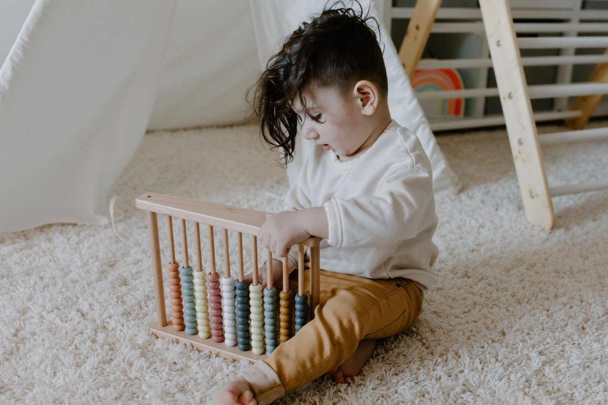 Tout-petit assis sur un tapis jouant avec un jouet éducatif en bois Montessori