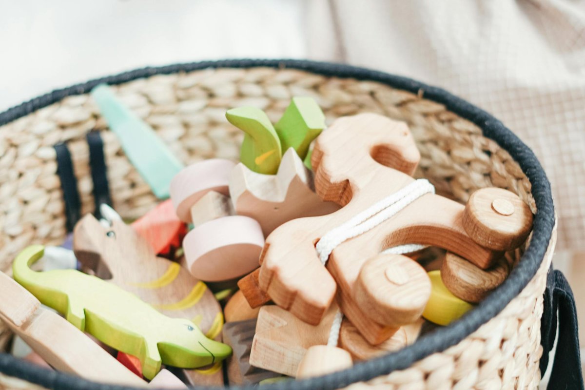 Main de bébé attrapant des jouets en bois dans un panier en osier