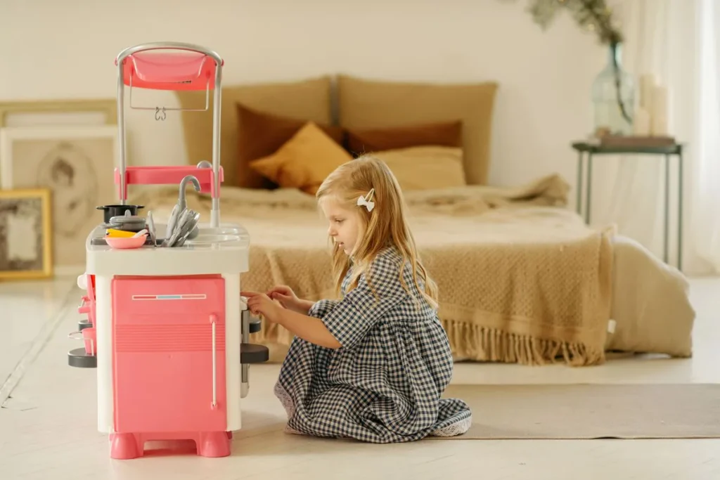 Petite fille qui joue avec sa cuisine enfant à hauteur adaptée