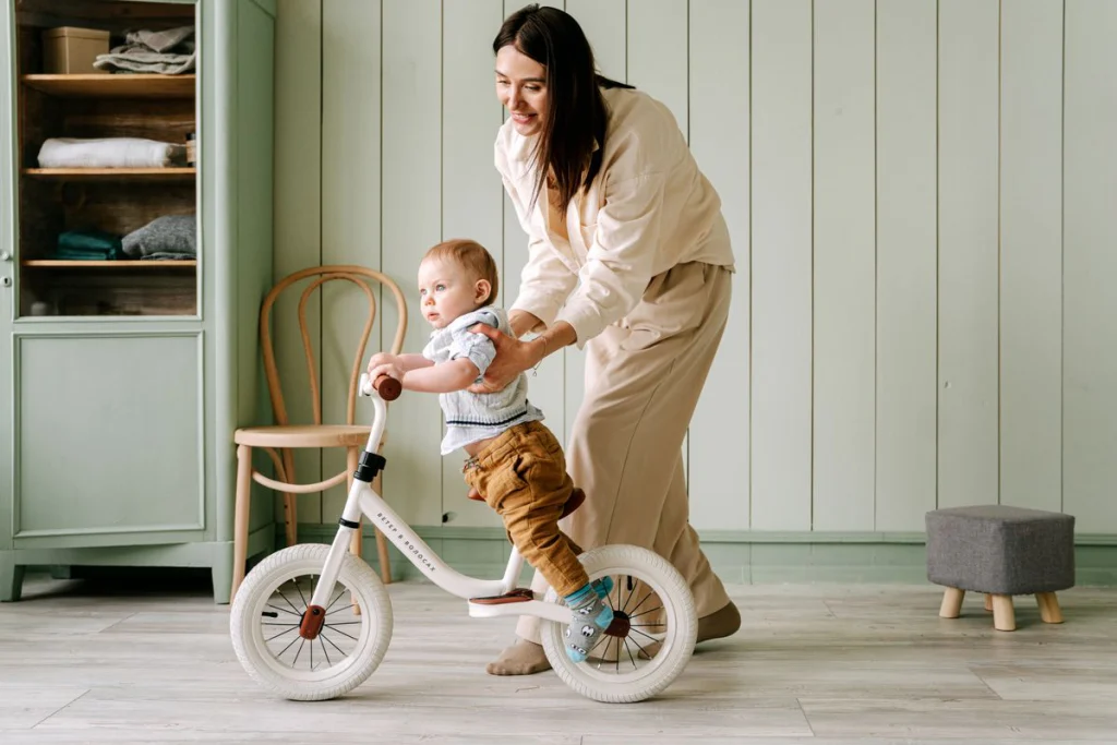 Parent accompagnant un jeune enfant qui apprend à se déplacer sur une draisienne