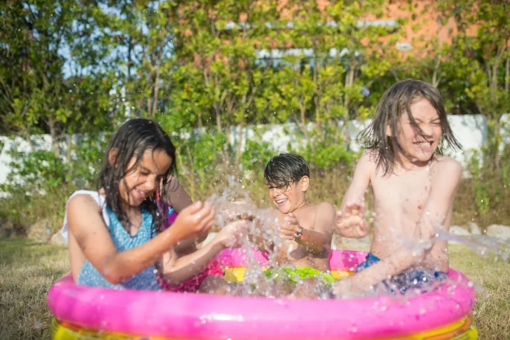 Trois enfants qui s'éclaboussent dans une piscine gonflable ronde de jardin
