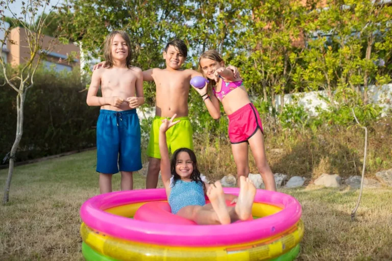 Quatre enfants qui jouent dans une piscine gonflable au fond d'un jardin en été