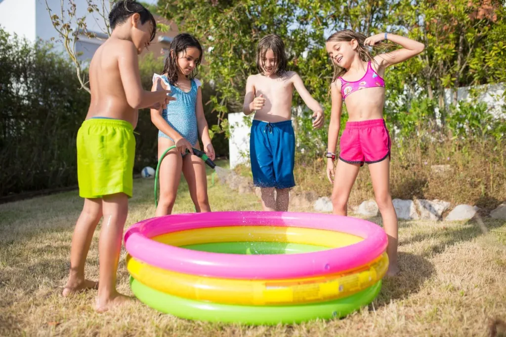 Piscine gonflable pour enfant remplie au tuyau d'arrosage dans un jardin