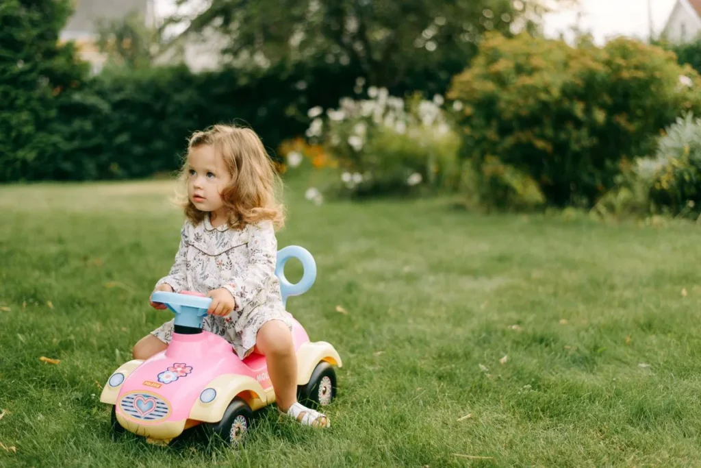 Enfant sur un porteur bébé en plastique dans l'herbe d'un jardin