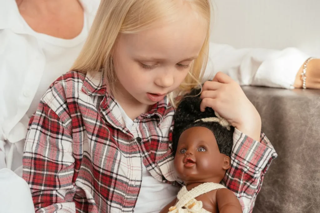 Enfant prenant soin de son poupon, en train de lui coiffer les cheveux