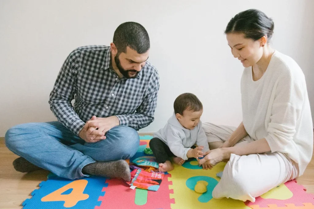 Parents et bébé assis sur un tapis puzzle en mousse aux couleurs vives