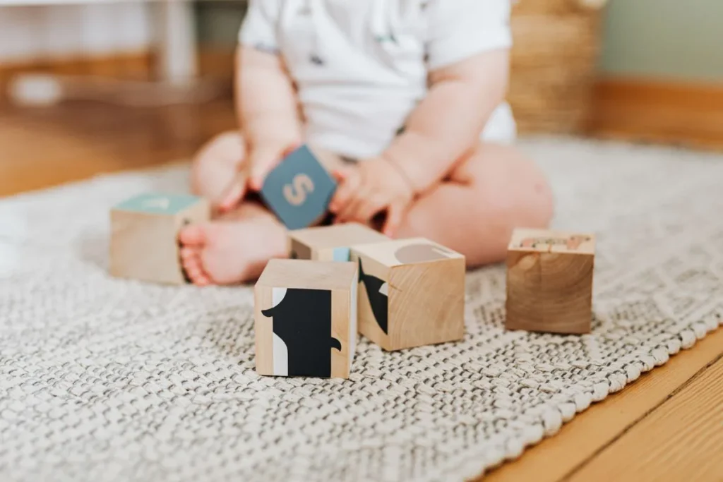 Bébé assis sur un tapis clair, manipulant des cubes en bois