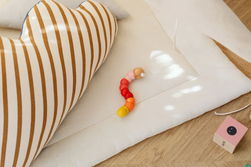 Tapis d'éveil uni et jouet en bois posés au sol, sans arche ni jouets suspendus