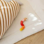 Tapis d'éveil uni et jouet en bois posés au sol, sans arche ni jouets suspendus