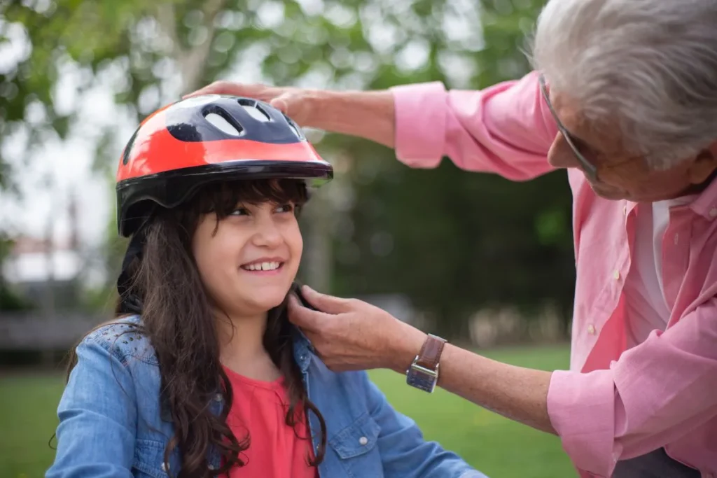 Un adulte ajuste le casque d'une enfant avant de partir en trottinette