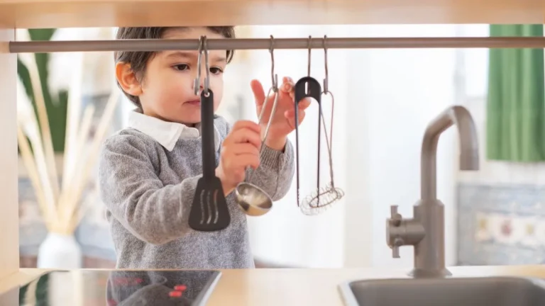 Enfant jouant à la dînette dans une cuisine d'imitation