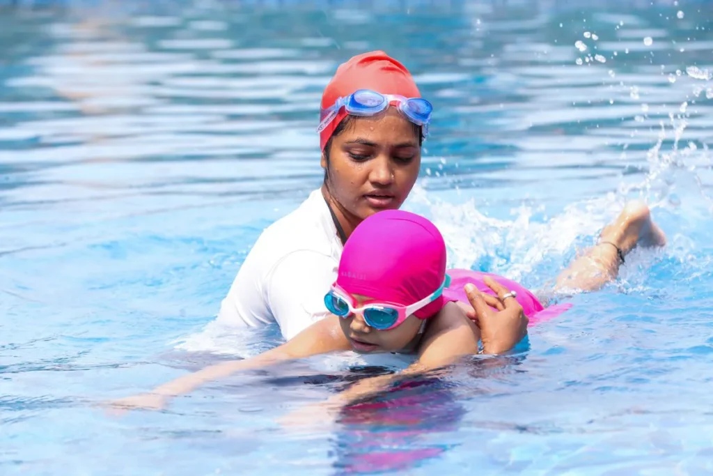 Maître-nageur guidant un enfant à la piscine pour apprendre à nager sans gilet