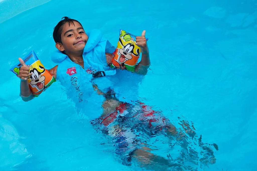 Enfant portant un gilet de piscine et des brassards dans un bassin