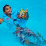 Enfant portant un gilet de piscine et des brassards dans un bassin
