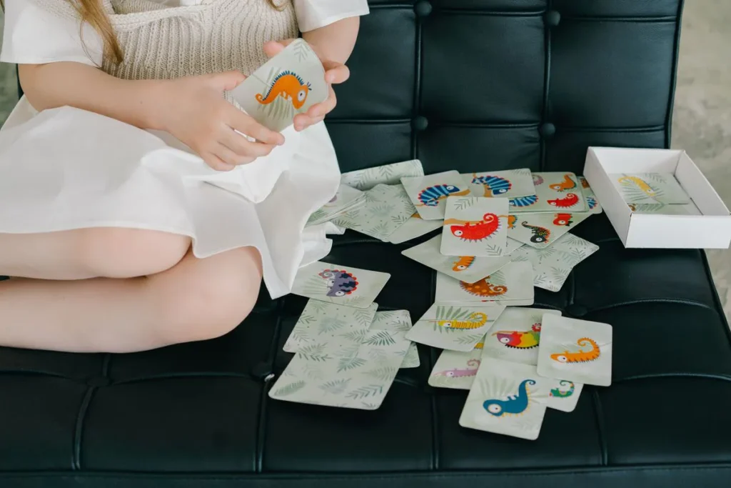 Enfant de 6 ans qui joue avec des cartes colorees sur un canape