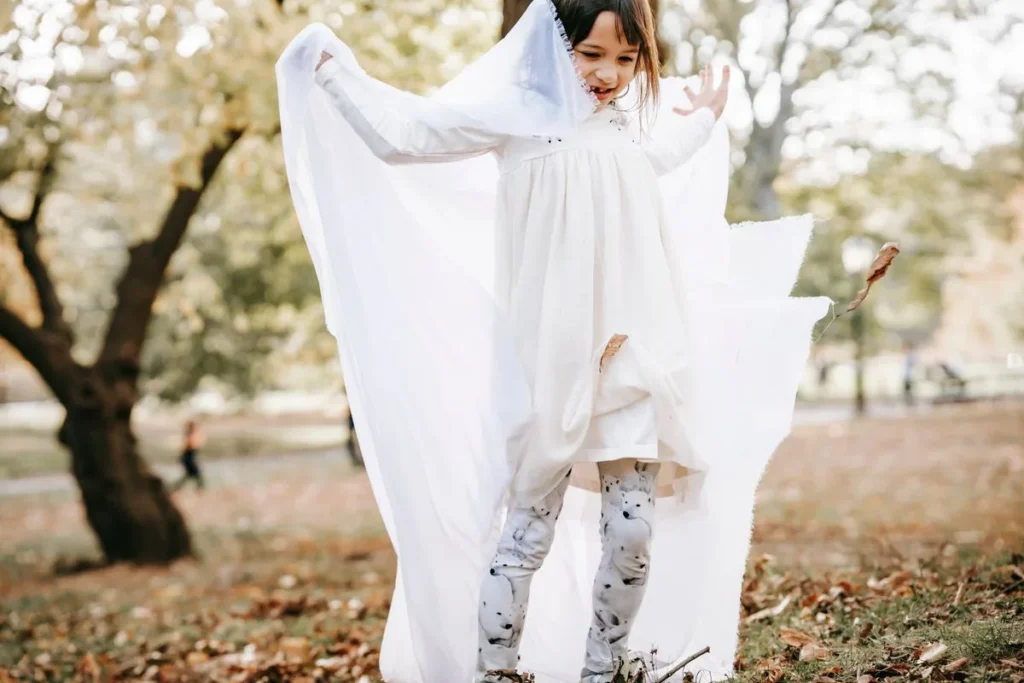 Fillette enfilant un drap blanc pour se fabriquer un déguisement de fantôme