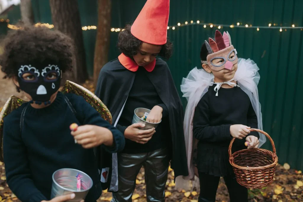 Trois enfants en déguisement d'Halloween ramassent des bonbons dans la rue le soir