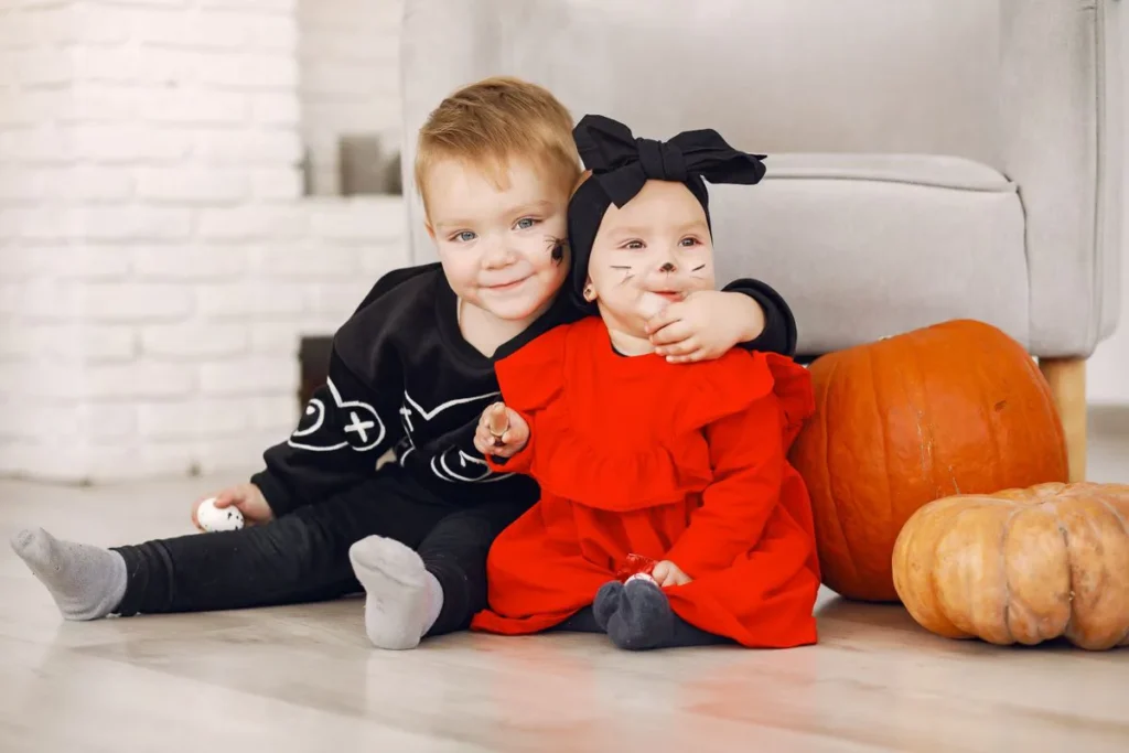 Deux tout-petits en déguisement d'Halloween assis près de citrouilles
