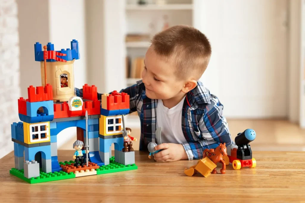 Garçon qui joue avec un château en briques et ses figurines, idée de cadeau à 4 ans