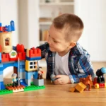 Garçon qui joue avec un château en briques et ses figurines, idée de cadeau à 4 ans